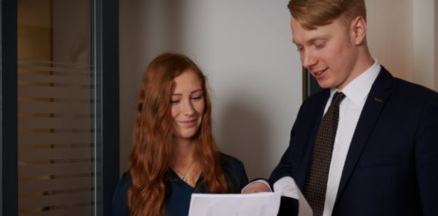 Colleagues reviewing documents together in an office setting, highlighting teamwork and collaboration.