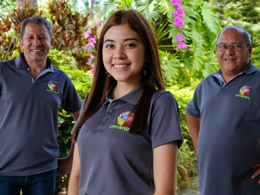 Die Teammitglieder lächeln gemeinsam im Freien und präsentieren ihre leuchtenden Uniformen inmitten üppiger tropischer Pflanzen.