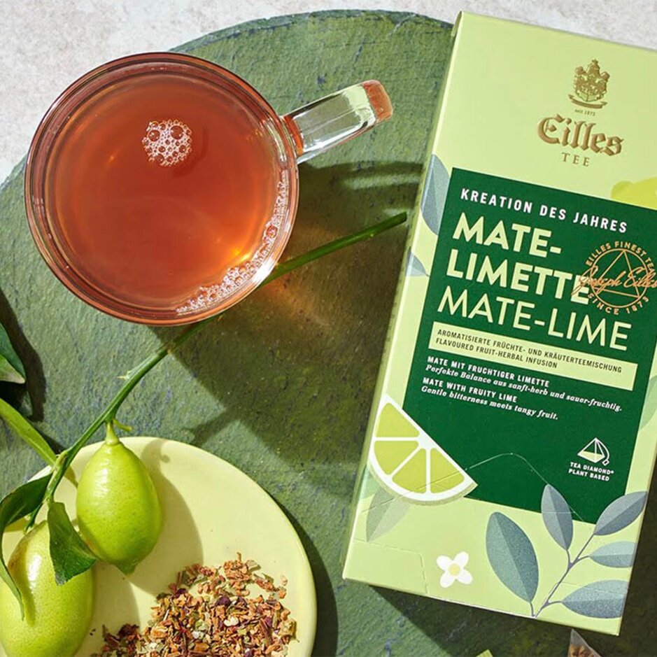 Erfrischender Eilles-Tee Mate-Limetten-Aufguss, serviert mit frischen Limetten und Kräuterzutaten auf einem rustikalen Hintergrund.