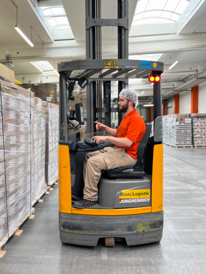 Lagerarbeiter, der einen Jungheinrich-Gabelstapler bedient und Paletten in einer effizienten Logistikumgebung manövriert.