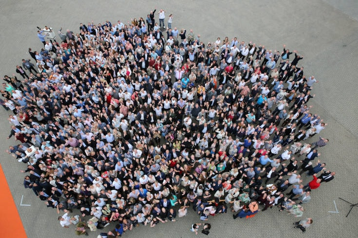 Aerial view of a large, engaged crowd celebrating teamwork at a corporate event, showcasing diverse professionals.