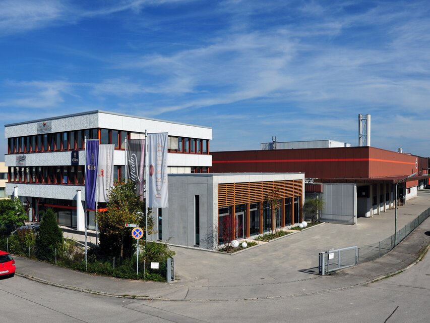 Modernes Industriegebäude in Sauerlach, mit Büros und einer Fabrik, unter blauem Himmel.