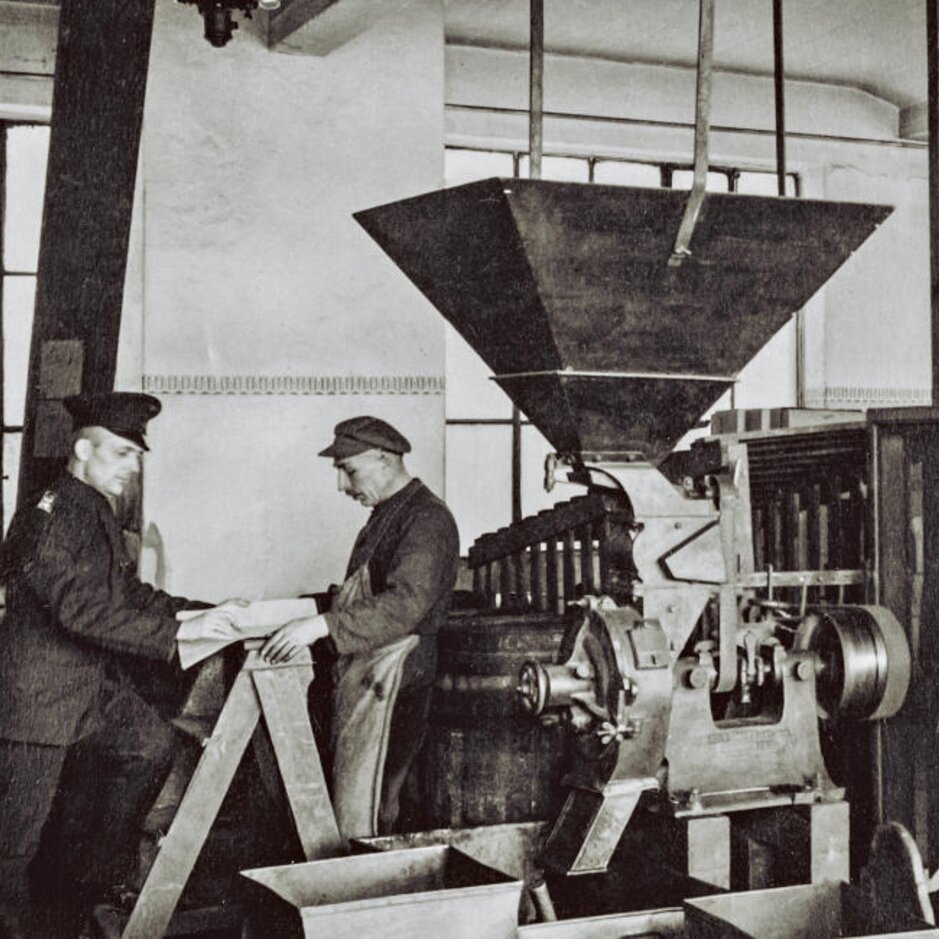 Historische Szene der Kaffeeproduktion mit Arbeitern und Maschinen in einer alten Rösterei. J.J. Darboven Erbe.