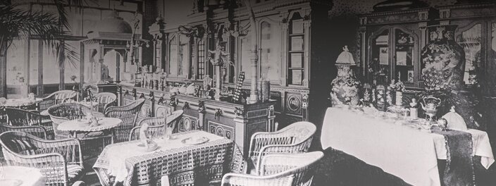 Historische Café-Einrichtung mit eleganten Möbeln und Dekorationsstücken, die den Charme und den Stil der alten Zeit widerspiegeln.