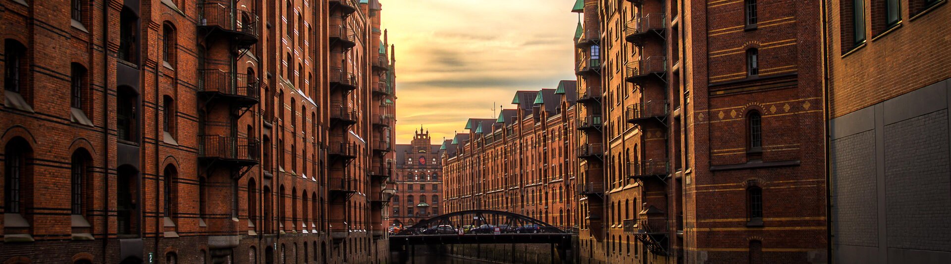 Historic Hamburg buildings lining a tranquil canal at sunset, showcasing the city's stunning architecture and charm.