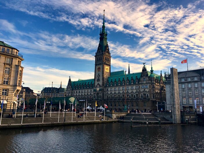 Hamburg City Hall beside the canal, showcasing its stunning architecture and vibrant sky on a clear day.