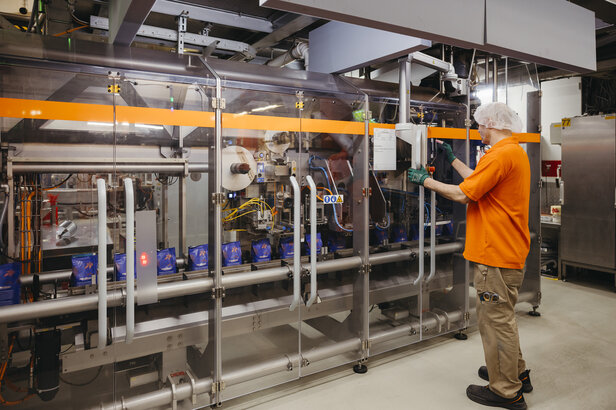 Arbeiter bei der Bedienung von automatisierten Verpackungsmaschinen in einer modernen Lebensmittelproduktionsanlage, die effiziente Prozesse demonstriert.