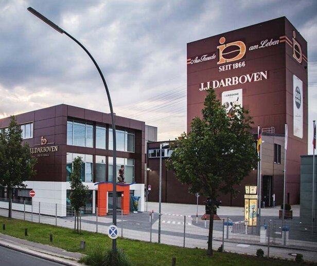 J.J. Darboven headquarters featuring modern architecture amidst trees and streetlights, showcasing the brand's history since 1866.