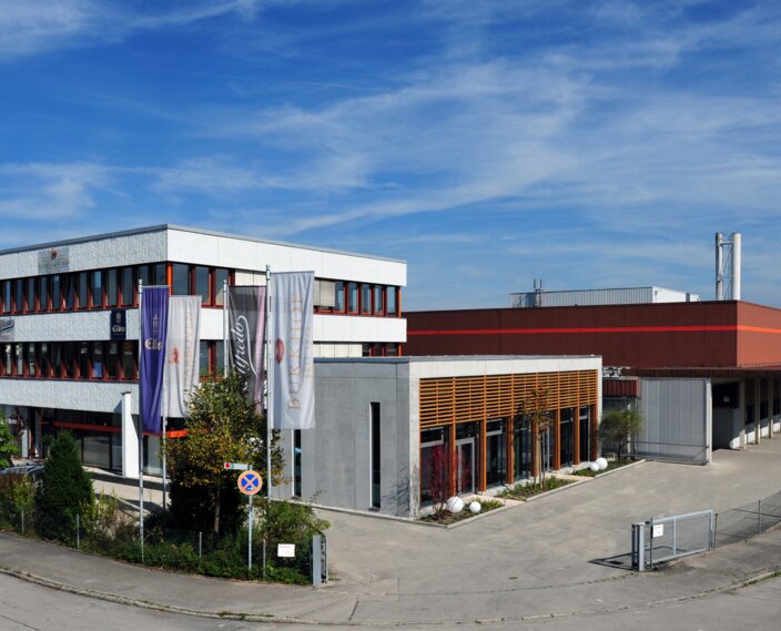 Modern industrial building in Sauerlach, featuring offices and a factory, under a clear blue sky.