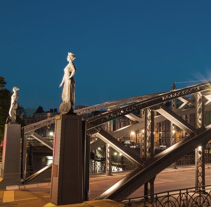 Die Brooksbrücke in Hamburg, nachts wunderschön beleuchtet, mit eleganten Statuen an beiden Enden, die architektonischen Charme versprühen.